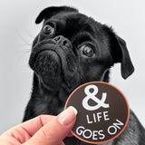 A cute dog and a And Life Goes On sticker. 