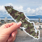 A Vancouver Island Camo sticker in front of a beach scene. 