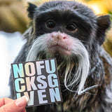 A hand holding a Nofucksgiven sticker in front of a  cute monkey. 