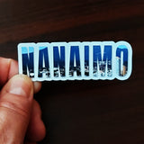 A hand holding a Nanaimo magnet. 